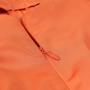 Detailed close-up of the hidden zipper on the orange high waist jumpsuit fabric