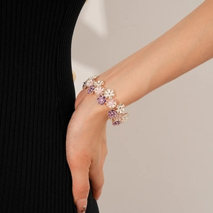 Detail eines rosa und lila Emaille-Blumenarmbands mit vergoldeter Metallkette für Damen