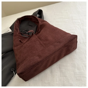 Detailed macro view of burgundy suede tote bag texture with vertical stitching and drawstring