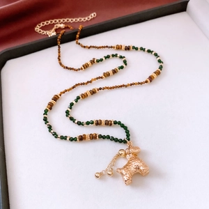 Détail du collier de perles avec pendentif chiot doré et perles en oeil de tigre