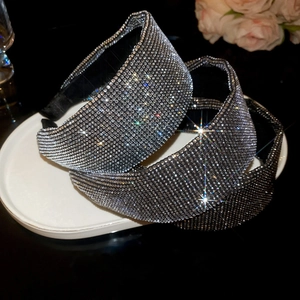 Detail of silver rhinestone headbands showing twisted and wide designs on a white plate