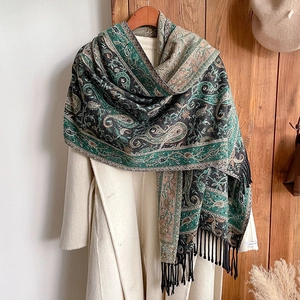 Ethnic paisley cashmere feel shawl with fringe draped over a beige winter coat