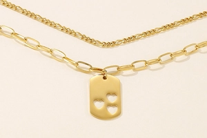Detail of gold double-layer necklace with square pendant and hollow heart shapes