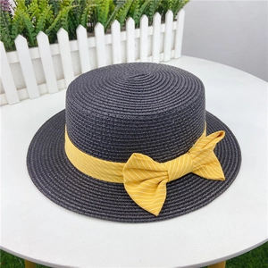 Detail of flat-top straw sun hat in dark grey with yellow striped bow on a table