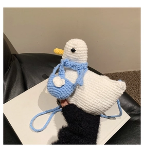 Detailed knit texture of a handmade white duck crochet bag with blue scarf and mini heart pouch