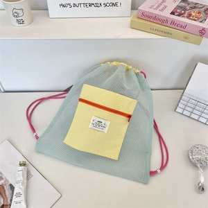 Détail du sac à cordon en filet vert menthe avec poche jaune et étiquette décorative