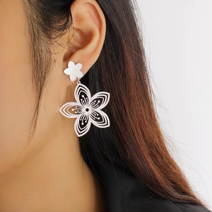 Detailed view of elegant silver floral earrings with hollow petals on a model's ear