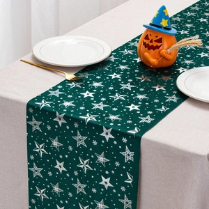 Close-up of dark green velvet table runner with silver snowflake patterns and festive setting