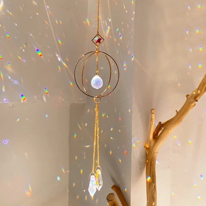 Detail of gold suncatcher with crystal spheres reflecting rainbow light on wall