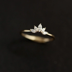 Macro shot of marquise-cut zircons and gold crown ring detailing against a dark background