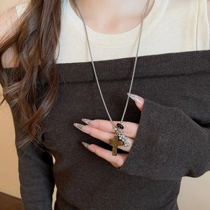 Detail of vintage long necklace featuring a brown cross pendant and silver beaded chain