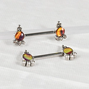 Close-up of stainless steel nipple rings with colorful sunflower gems on white silk