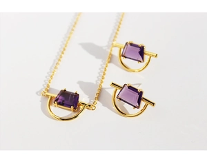 Detailed close-up of gold plated brass jewelry set with purple rectangle zircon stones