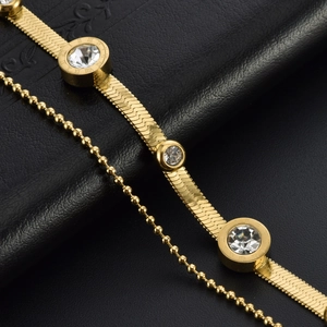 Double-layer gold titanium bracelet featuring snake chain and zircon charms on black leather