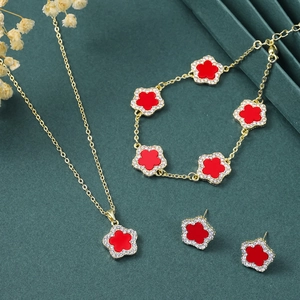 Elegant gold jewelry set featuring red five-petal flowers with pavé diamond accents
