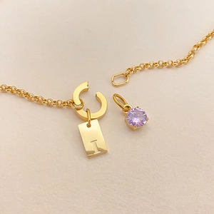 Detail of gold stainless steel DIY necklace with letter I and purple crystal charms