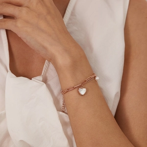 Close-up of double-layer rose gold bracelet with heart shell pendant and white pearl detail