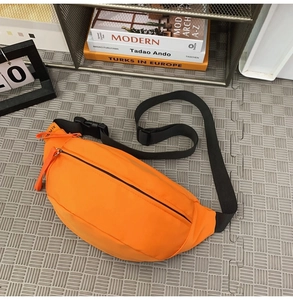 Close-up of bright orange waterproof nylon chest bag on a minimalist textured surface