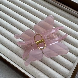Detail of pink translucent butterfly hair claw with gold spring on a jewelry tray