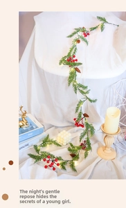 Close-up of artificial Christmas garland with red berries, pine cones and LED fairy lights