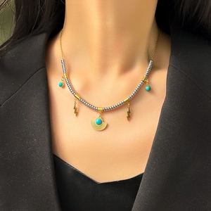 Detail of beaded turquoise necklace with lightning bolt charm on a black blazer
