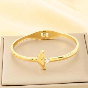 Detail of 18K gold plated fish tail bracelet with sparkling zircon on a silk background