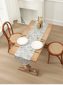 Detailed view of woven jacquard floral table runner with grey-white base and tassels