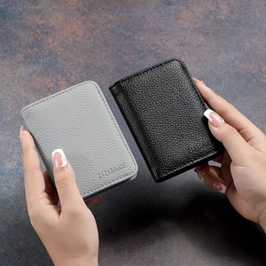 Detailed view of black and grey litchi grain leather card holders in hand