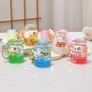 Close-up of colorful liquid cat keychains in pink, blue, and green on white stand