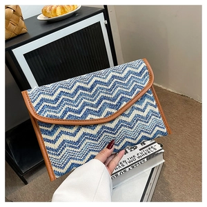 Detail of blue and white wavy chevron straw envelope clutch with brown leather trim finish