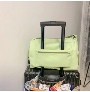 Sac de voyage vert clair fixé à la poignée d'une valise montrant le manchon arrière pratique