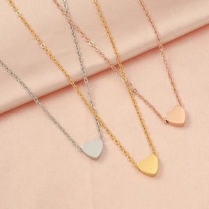 Three heart pendant necklaces in silver, gold, and rose gold on pink silk satin fabric