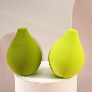 Pear-shaped makeup sponges in green tones on a white pedestal for flawless application