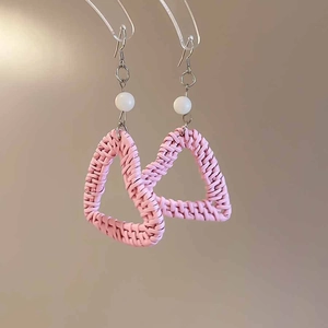 Detail of pink woven resin heart earrings with white beads for a seaside vacation style