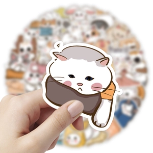 Close-up of cute hand-drawn white cat sticker held over a stack of colorful animal decals