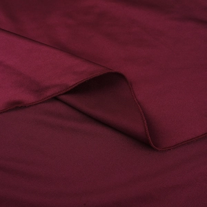 Macro detail of wine red satin fabric showing silky sheen and fine twill texture