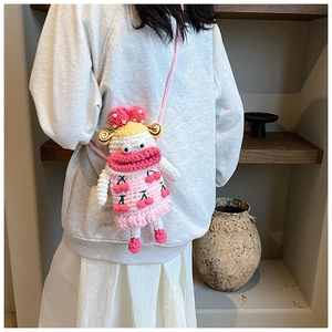 Detail of pink knitted doll crossbody bag with cherry patterns and pearl accents on model