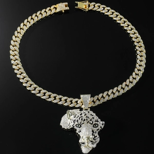 Close-up of golden Africa map pendant with crystal leopard head and green gemstone eyes