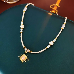 Macro detail of 18K gold sunflower pendant with pink stone on beaded necklace