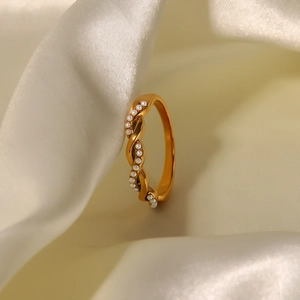 Twisted gold titanium steel ring featuring elegant pearls on a beige silk background