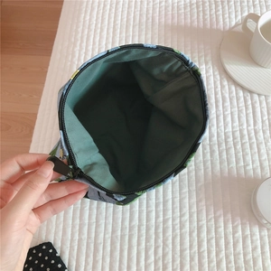 Detail of floral jacquard canvas makeup bag showing green inner lining and zipper