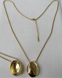 Vue détaillée d'un collier pendentif ovale en or poli avec une chaîne à billes