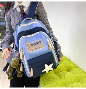 Detail of school backpack with multiple compartments and cute frog plush accessory