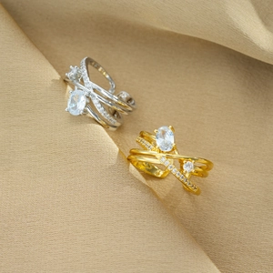 Close-up of gold and silver multi-layer crisscross rings with oval zircon on silk fabric