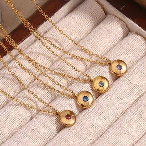 Macro shot of 18K gold plated birthstone pendants in red blue and purple on a soft lining