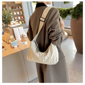 Detail of cream quilted tote bag showing adjustable shoulder strap on a model