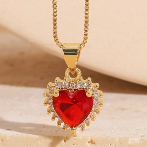 Macro shot of 14K gold plated heart pendant with red stone and zircon pavé detailing