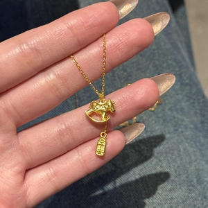 24K gold plated necklace with rocking horse pendant and lucky charm on blue denim background