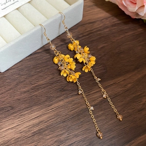 Macro view of long osmanthus tassel earrings with yellow flowers on wooden surface