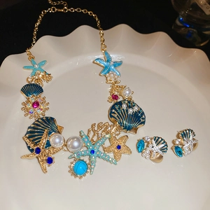 Detail of starfish and shell jewelry set with pearls on a white shell-shaped display tray